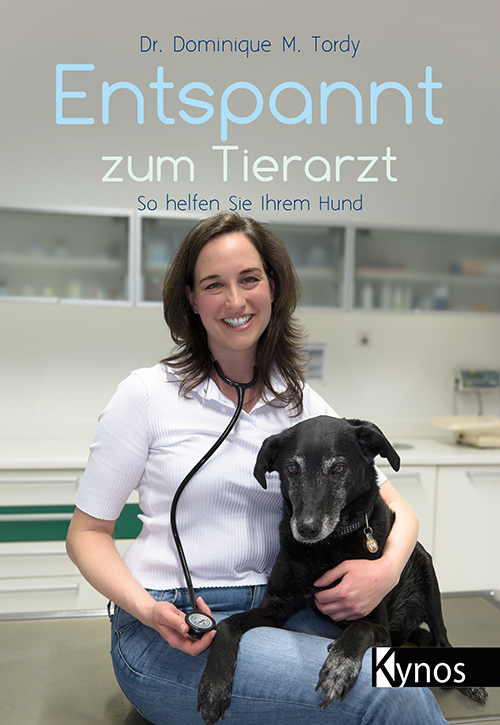 Tierärztin und Hund sitzen auf einem Behandlungstisch